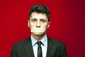businessman with mouth taped against red background, NDA concept