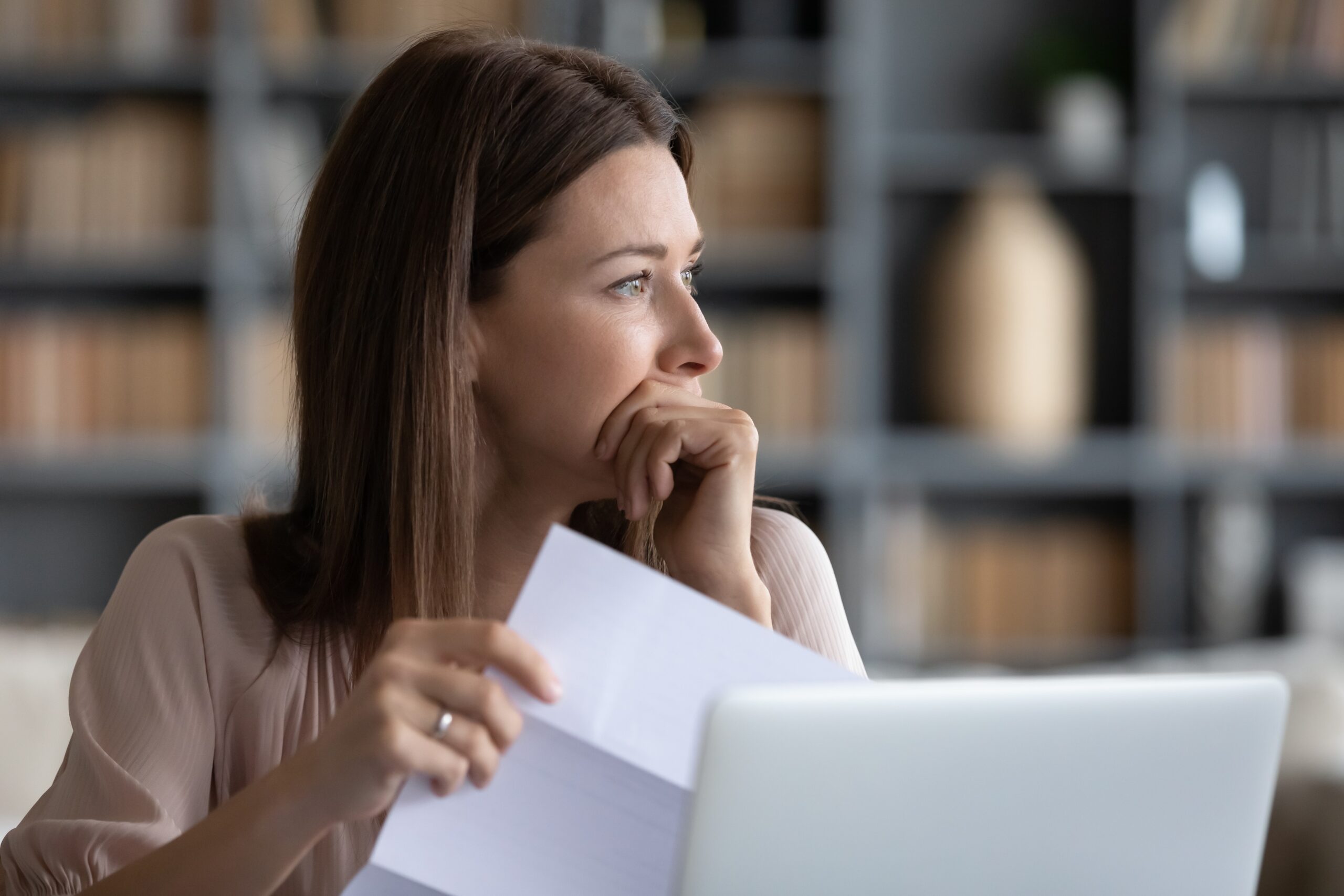 Pensive young woman broods while holding piece of paper, closure concept