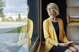 Businesswoman wearing spectacles looking thoughtfully out of window, funding options business