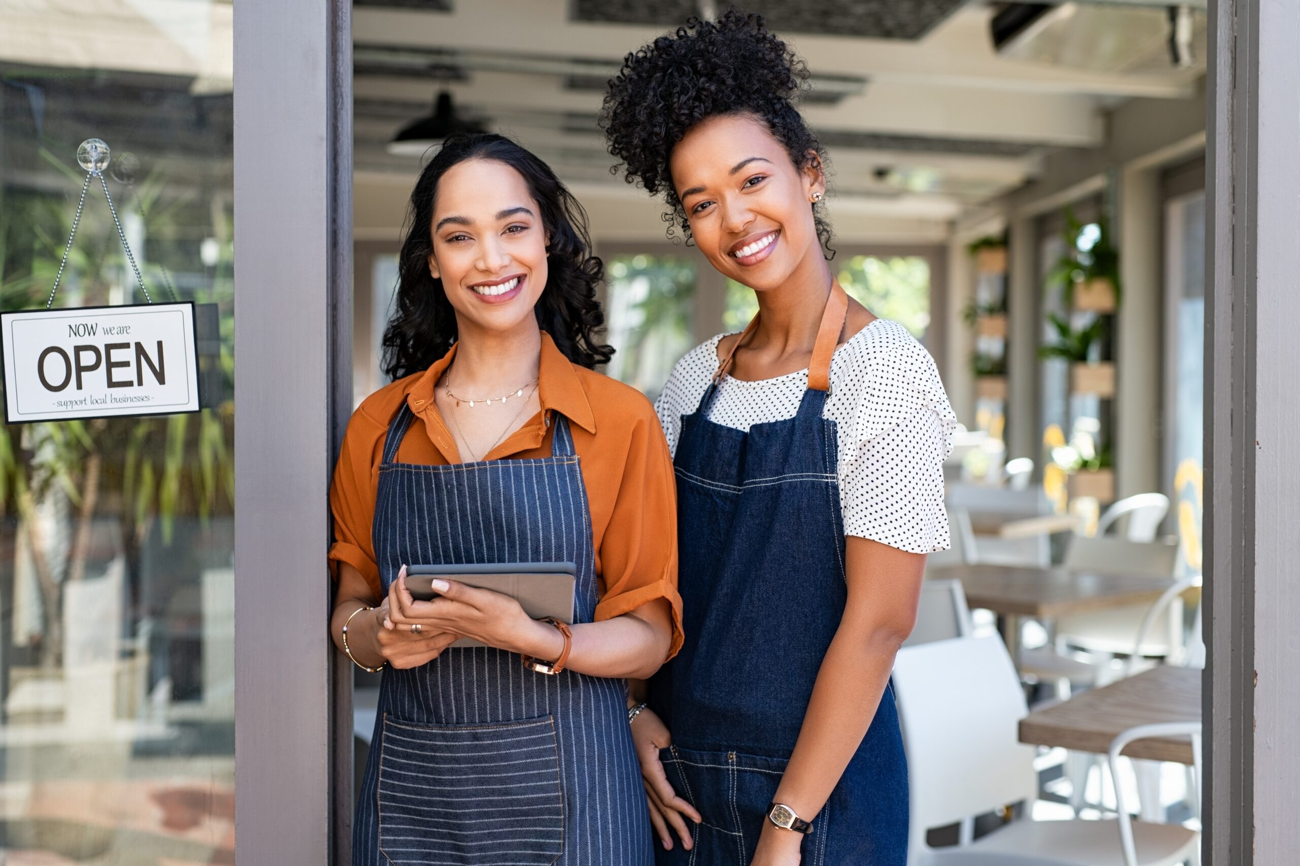 Two smiling cafe owners with Open sign, Business Essentials concept