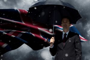 Brexit small businesses concept. English businessman with umbrella in storm standing in front of Union Jack