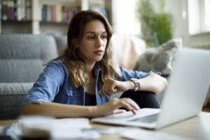 Self-employed Making Tax Digital concept. Young woman staring at laptop and looking at watch