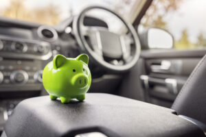 Company car tax concept. Green piggybank sitting in car interior