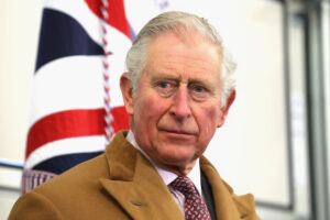 Royal warrant concept. King Charles III looking pensive with Union Jack flag behind him