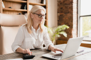 Employment Allowance concept. Bespectacled blonde woman sitting at laptop