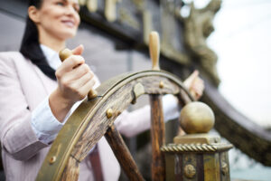 Self-employment concept. Woman gripping sailing wheel of old ship