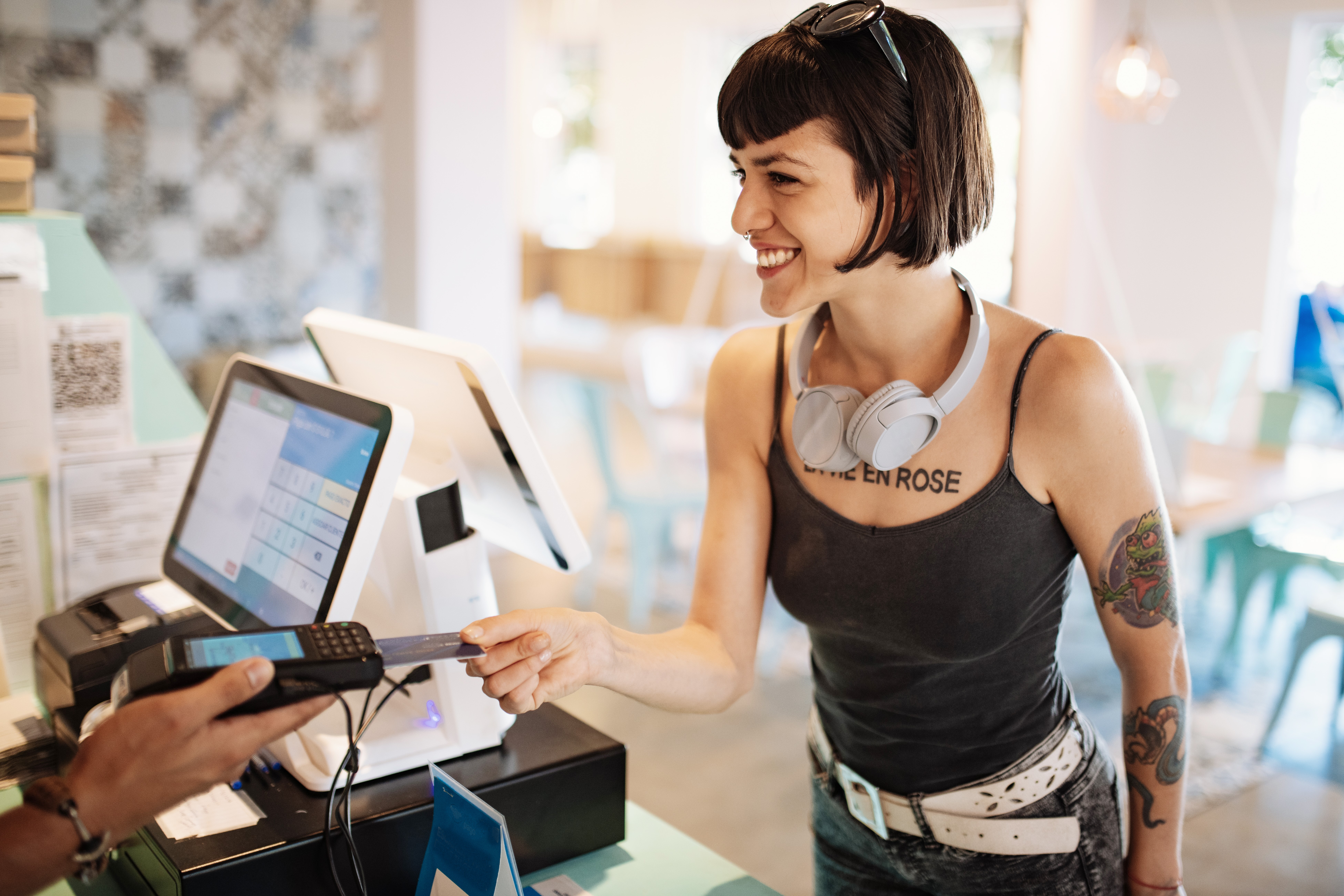 POS system concept. Cool Latina millennial having card payment accepted at payment terminal