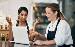Shot of two women using a laptop together while working in a cafe
