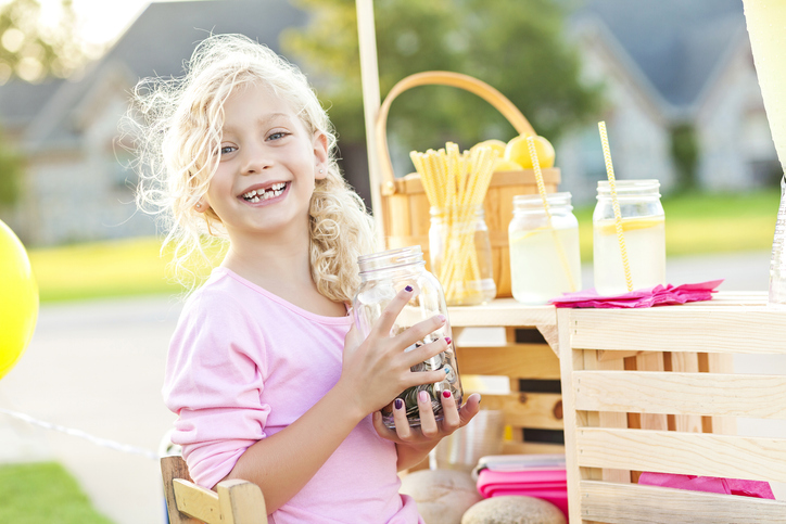 Cute smiling girl holding up her earnings from selling lemonade