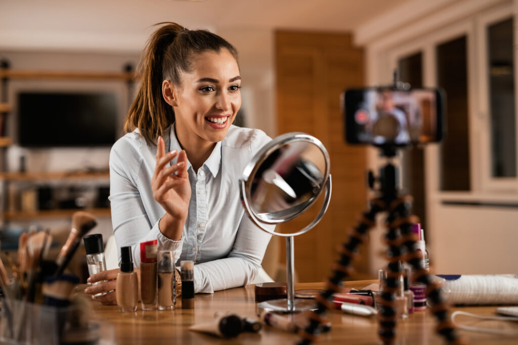 Young happy woman recording make-up vlog at home.
